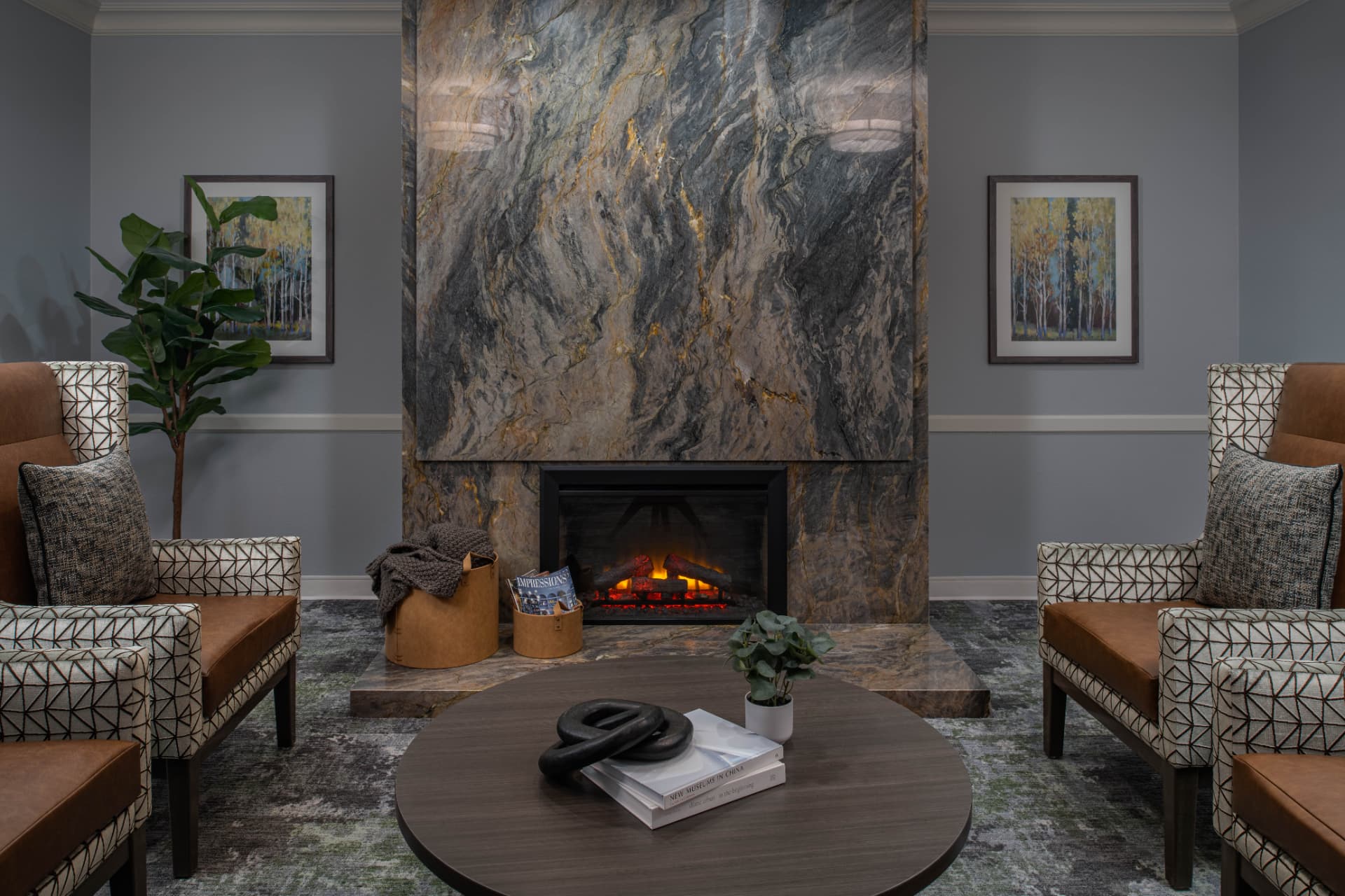 Living room with patterned armchairs and a round coffee table beside a marble fireplace