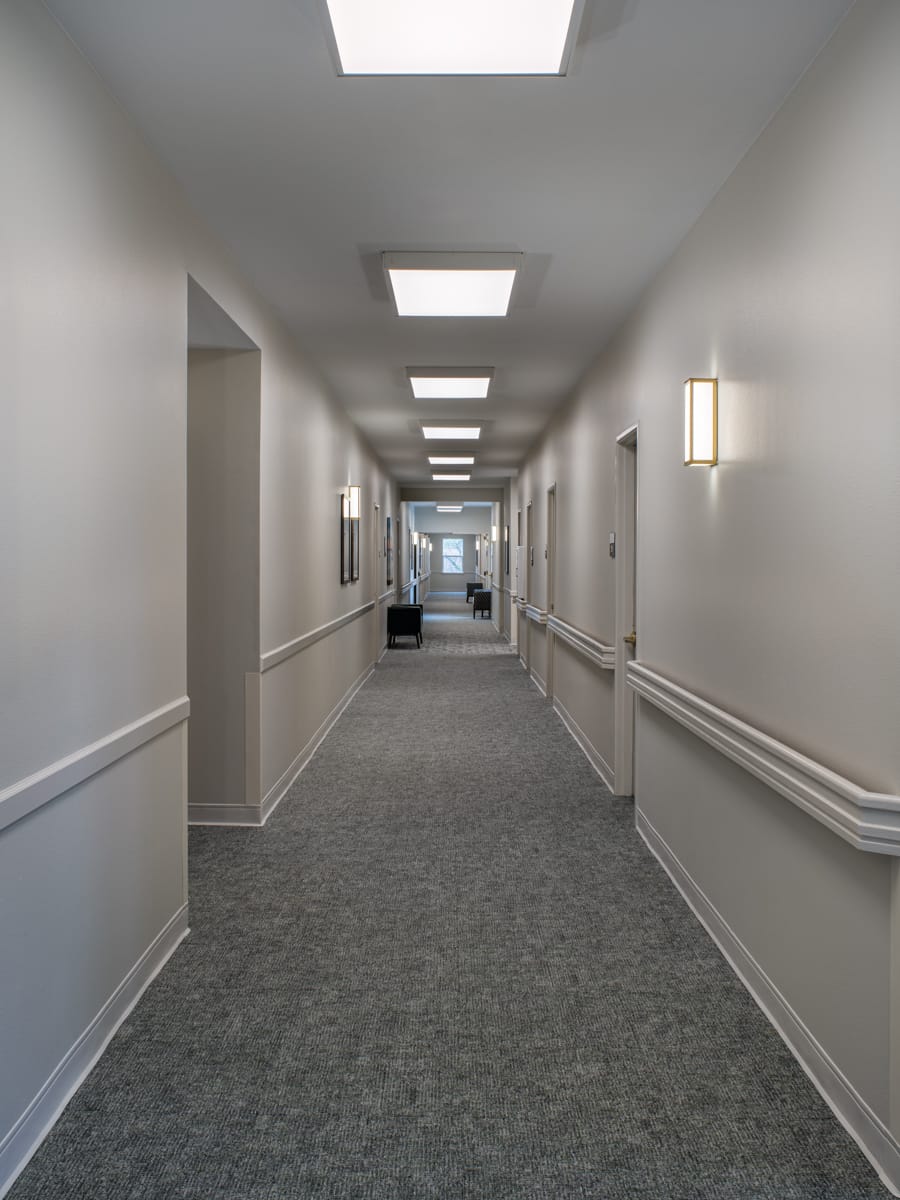 Residential corridor at The Meadows with handrails and wall sconces