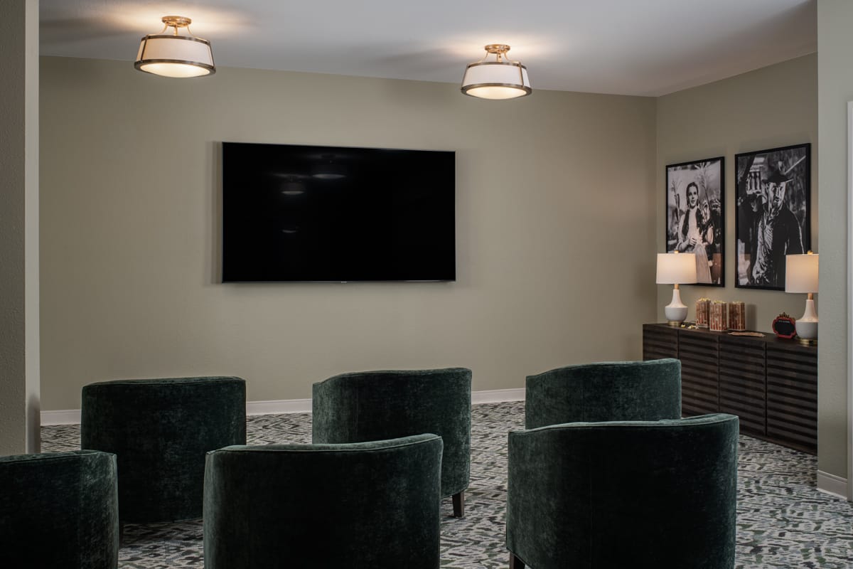 Media room with green velvet armchairs facing a wall-mounted screen